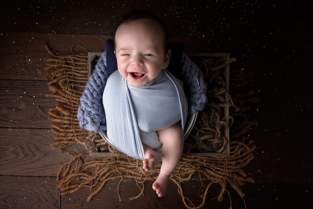 Older Newborn wrapped in blue and smiling