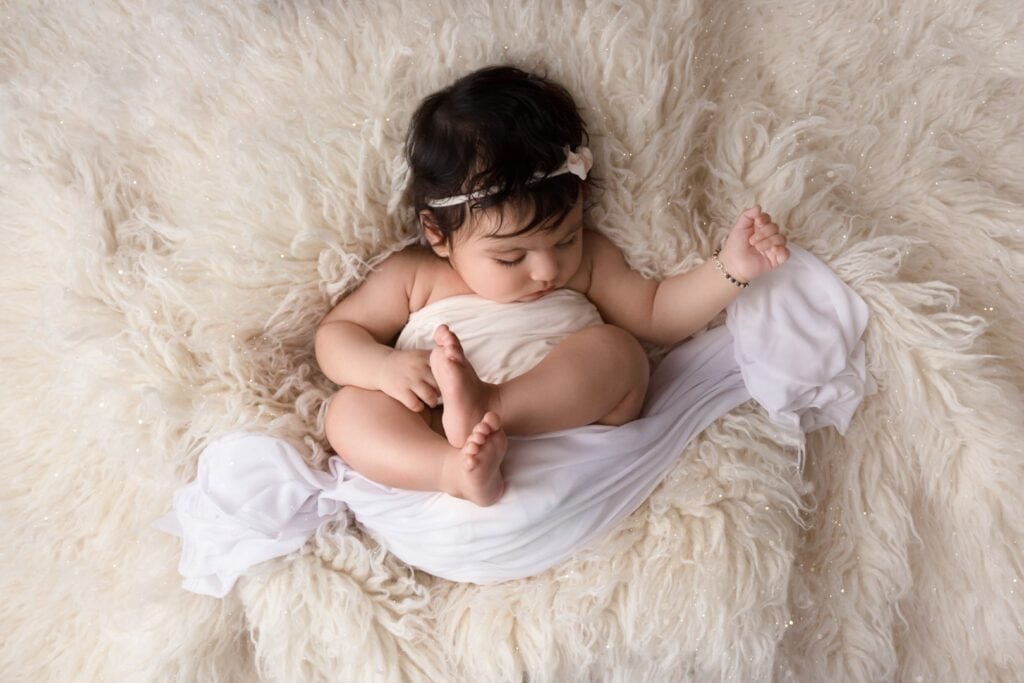 Older newborn sleeping on cream rug