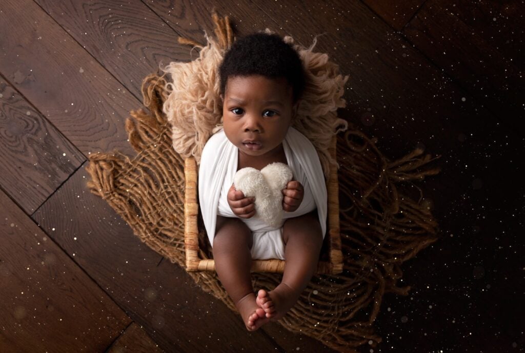 Older newborn holding heart