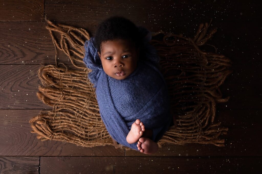 Older newborn wrapped in blue in box
