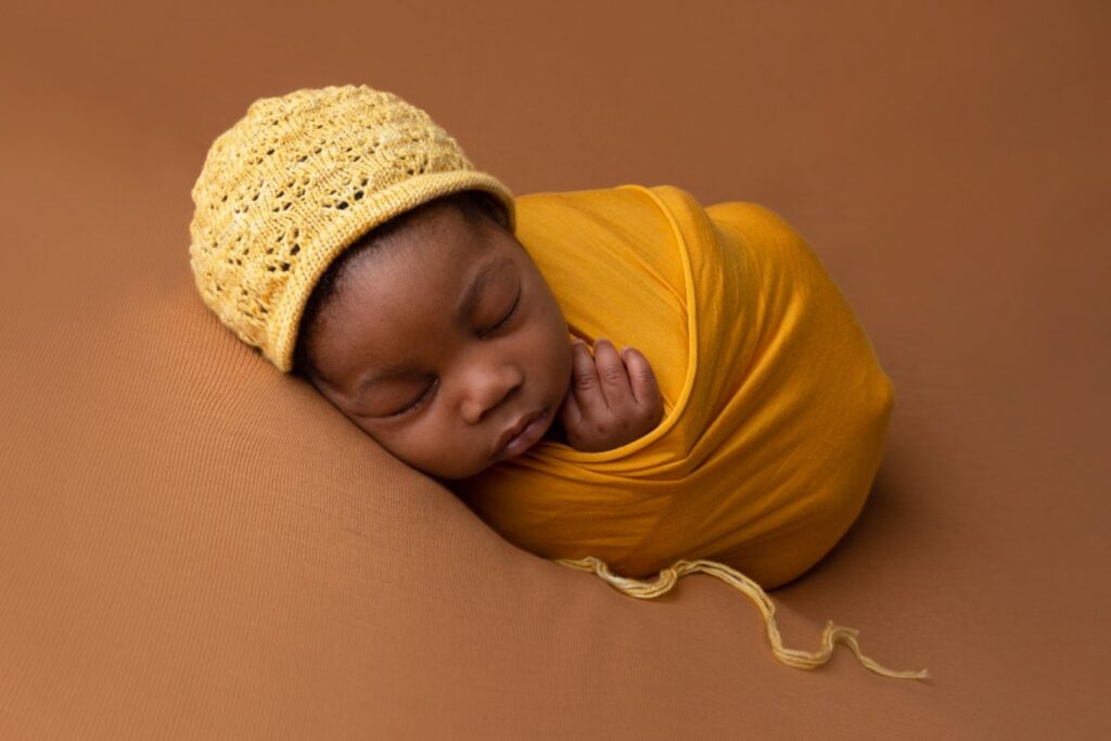Older newborn in mustard wrap and bonnet