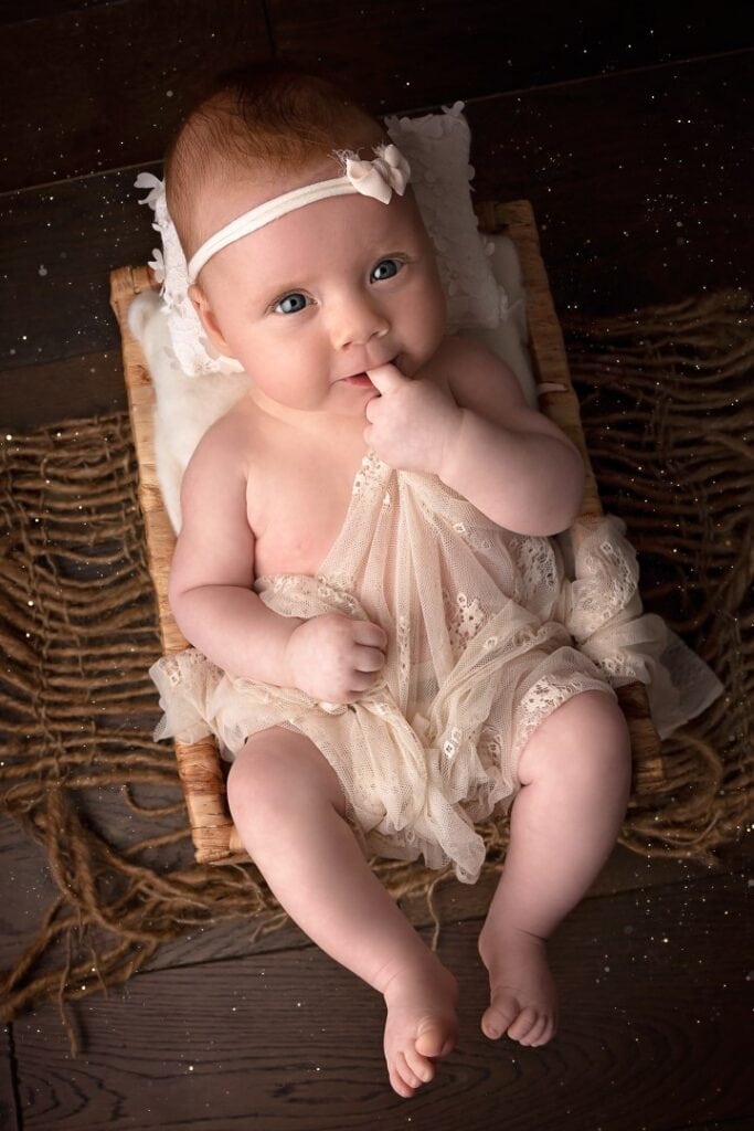 Older newborn with headband in wicker basket