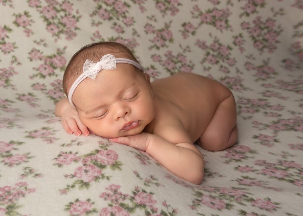 newborn session with baby sleeping on floral backdrop with headband on